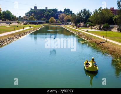 Due ragazze che cavalcano un pedalo sul fiume Fuengirola con il castello di Sohail sullo sfondo. Foto Stock