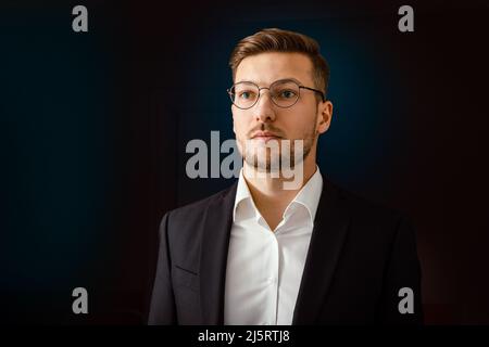 Ritratto di un uomo d'affari in abito su sfondo scuro. Foto Stock