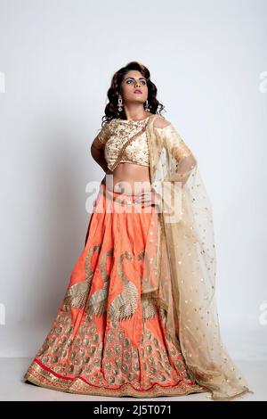 Bella donna indiana in un lehenga choli dorato e arancione Foto Stock