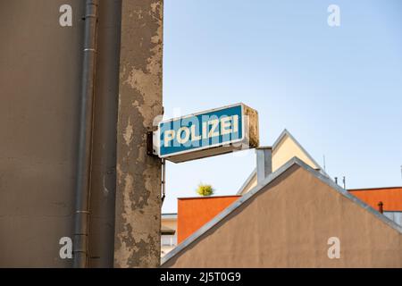 La polizia firma in Germania su un muro di un edificio. Segnaletica di una stazione di polizia in città. Una facciata scura con intemperie e crepe nell'intonaco da parete. Foto Stock