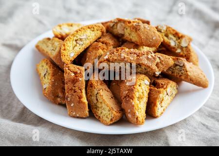 Cantuccini italiani fatti in casa con mandorle su un piatto bianco, vista laterale. Biscotti croccanti alle mandorle. Primo piano. Foto Stock