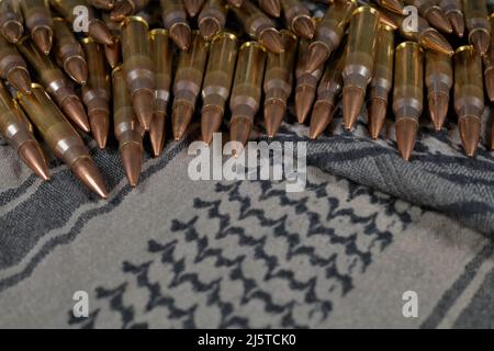 munizioni di calibro .308 su sfondo di tessuto verde-grigio (keffiyeh) Foto Stock