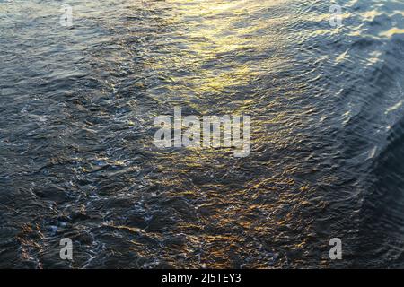 Sfondo scintillante d'acqua. Increspa con la luce del sole . Riflessione crepuscolare nel mare Foto Stock