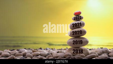 il nuovo anno 2023 sarà presto disponibile. Inizio anno nuovo 2023. Anni scritti sulla torre di pietra. Dati dell'anno dal 2018 al 2023. Tramonto sullo sfondo Foto Stock