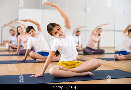 Ragazza che pratica yoga in studio con la famiglia Foto Stock