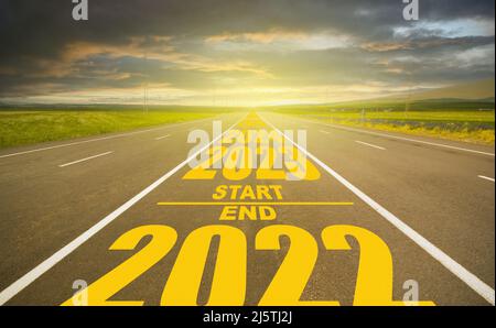 2022 fine e inizio 2023 strada scritta. Anno numero 2023 al tramonto drammatico e su strada vuota. Obiettivo e concetto di visione nel nuovo anno. Foto Stock