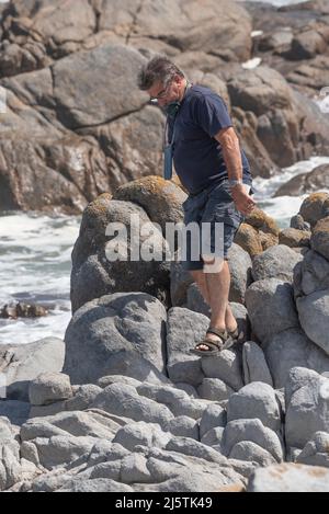 Costa occidentale, Sudafrica. 2022. Uomo che si arrampica sulle rocce in una località balneare sulla costa occidentale, Sudafrica Foto Stock