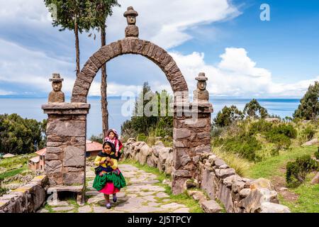 Una madre Taquileno e bambino camminando lungo il percorso dal porto alla città, Taquile Island, Lago Titicaca, Puno, Perù. Foto Stock