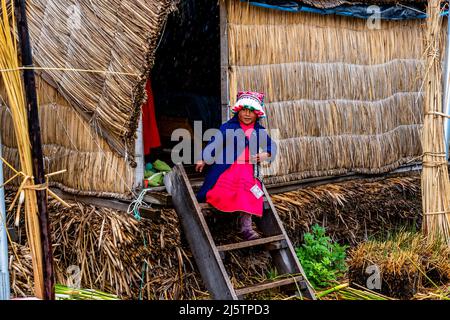 Un bambino di Uros lascia la sua casa sulle isole galleggianti di Uros, lago Titicaca, Puno, Perù. Foto Stock