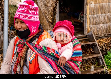 Una madre di Uros e bambino sulle isole galleggianti di Uros, lago Titicaca, Puno, Perù. Foto Stock