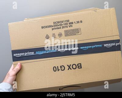 Parigi, Francia - Apr 25, 2022: Mano maschio POV con nuovo pacchetto corrugato ecologico con logo Amazon prime online shopping e commerce Foto Stock
