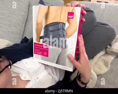 Parigi, Francia - Apr 25, 2022: Mano donna guardando la scatola di cartone di supporto lombare per il rilievo delle facciate giunti faccetta in cumino prodotto da medi Germania Foto Stock