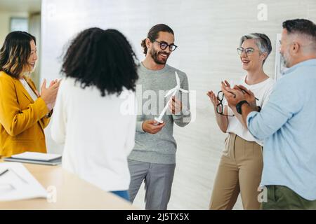 I professionisti del design felici applaudono allegramente durante una riunione in un ufficio creativo. Team di imprenditori innovativi che festeggiano i loro risultati Foto Stock