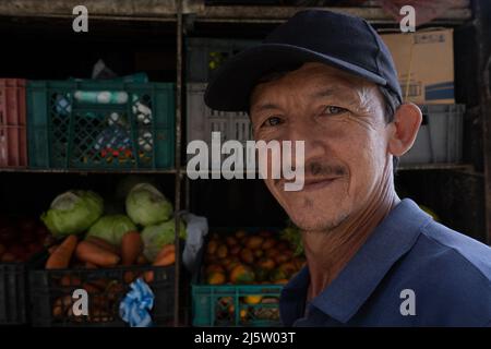 Uomini lavoratori latini in strada distributore di alimentari stand con verdure e frutta in strada Foto Stock