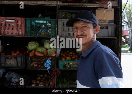 Uomini lavoratori latini in strada distributore di alimentari stand con verdure e frutta in strada Foto Stock