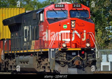 Elgin, Illinois, Stati Uniti. Una singola locomotiva Canadian National Railway conduce un treno merci intermodale attraverso una traversata di diamanti. Foto Stock