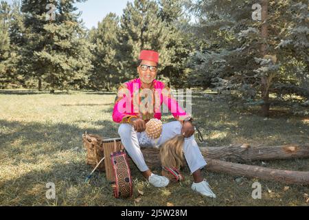 Bell'uomo africano in costume nazionale suona un tamburo etnico, djembe. Foto Stock