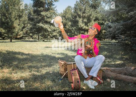 Bell'uomo africano in costume nazionale suona un tamburo etnico, djembe. Foto Stock