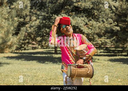 Bell'uomo africano in costume nazionale suona un tamburo etnico, djembe. Foto Stock