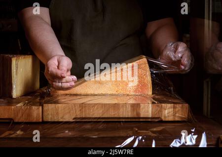 Un pezzo di formaggio viene confezionato sul banco. Foto Stock