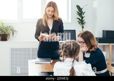 Lezione di scuola di istruzione insegnante donna leggere il libro alle sue alunne. Foto Stock