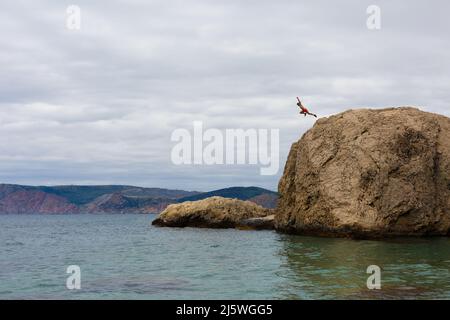 Brave Man salta da High Cliff Rock in acqua di mare Foto Stock