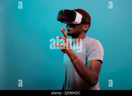 Il giovane si diverte con le cuffie per realtà virtuale interattive, utilizzando la tecnologia moderna con la visione futuristica 3D. Occhiali da gioco per adulti da millennial con simulazione visiva per il tempo libero. Foto Stock