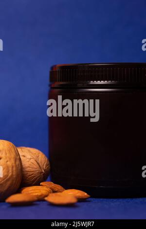 vaso nero con noci su sfondo blu. Foto Stock