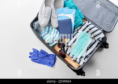 borsa da viaggio piena di vestiti, guanti e maschere Foto Stock