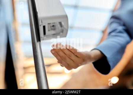 primo piano di donna al dispenser con igienizzatore per le mani Foto Stock