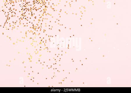 Dispersione di confetti dorati su sfondo rosa. Foto Stock