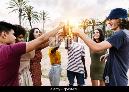 Gruppo di giovani amici allegri multirazziali con bevande in festa estiva Foto Stock