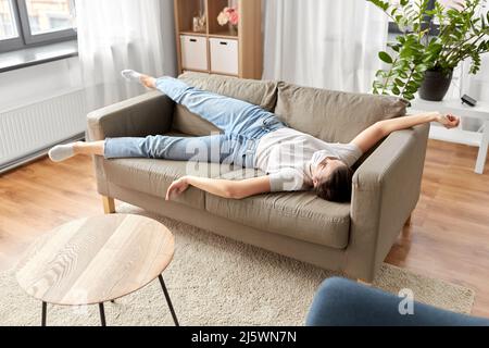 donna malata in maschera medica sdraiata sul divano a casa Foto Stock