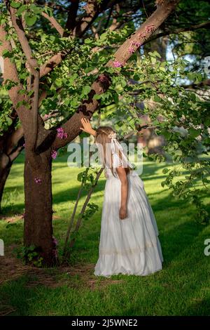 Ragazza vestita come comunione in un parco circondato dalla natura e dal colore Foto Stock