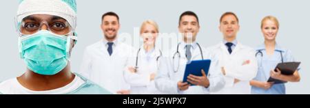 primo piano di chirurgo indiano in maschera e medici Foto Stock