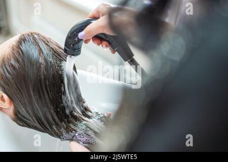 Vista ravvicinata del lavaggio dei capelli nel lavandino nel salone di bellezza Foto Stock