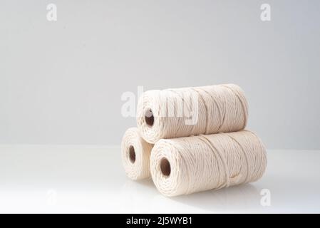 fili di macrama le bobine avvolte di colore beige naturale si trovano su uno sfondo chiaro Foto Stock