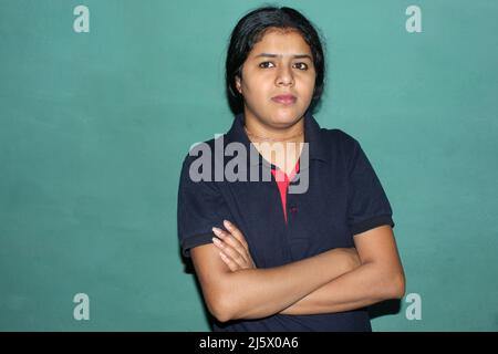 giovane felice allegra positiva sorridente ragazza con le mani incrociate indossare abito rosso isolato su sfondo verde Foto Stock