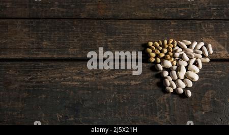 Legumi (fagioli). Molti tipi di fagioli secchi. Fagioli bianchi e verdi su una texture di legno. Cibo. Chiudi. Fagioli bianchi fagioli verdi. Snack brasiliano dieta. Foto Stock