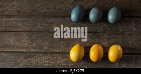 Uova dipinte per Pasqua nei colori della bandiera dell'Ucraina. Giallo e blu (ciano). Su tessitura di legno. Concetto: Cibo, vacanze, guerra in Ucraina Foto Stock