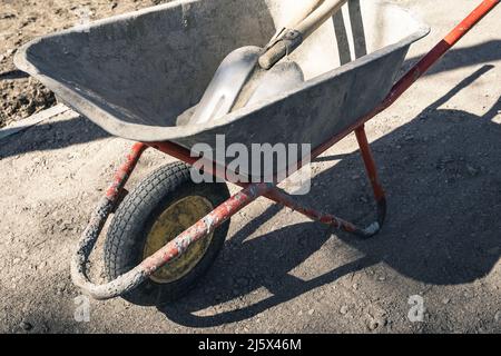 carriola di lavoro vecchia e affidabile con pale in cantiere Foto Stock