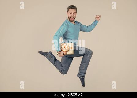 saltando bell'uomo con scatola presente. uomo d'affari che dà regalo di compleanno. uomo energico unshaven Foto Stock