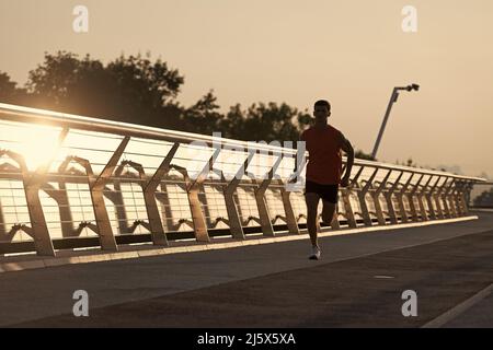 Il corridore atletico dell'uomo di misura corre sulla passeggiata in sera, running Foto Stock