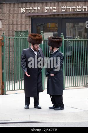 Durante la Pasqua, gli uomini ebrei assidici che indossano cappelli in pelliccia di shtreimel hanno una conversazione all'esterno di una sinagoga su Bedford Ave. A Williamsburg, Brooklyn, N. Foto Stock