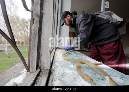 BORODIANKA, UCRAINA - 26 APRILE 2022 - Un uomo prende le barrette di vetro in un centro di risorse inclusive danneggiato durante l'invasione russa durante il restauro Foto Stock