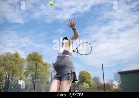 Donna incinta che gioca a tennis Foto Stock