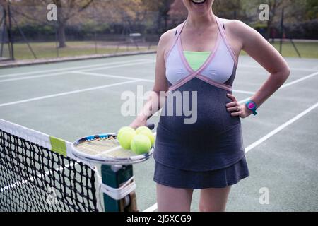 Ritratto donna incinta in abito sul campo da tennis Foto Stock