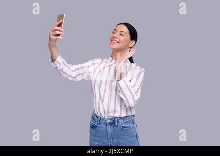 Ragazza che ha videochiamata sul telefono che ondina mano isolata. Videochiamata ragazza. Ragazza che usa il telefono. Isolato Foto Stock