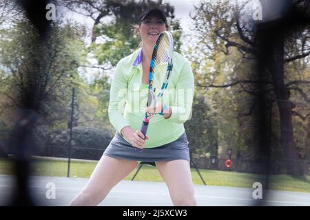 Donna incinta che gioca a tennis sul campo da tennis Foto Stock