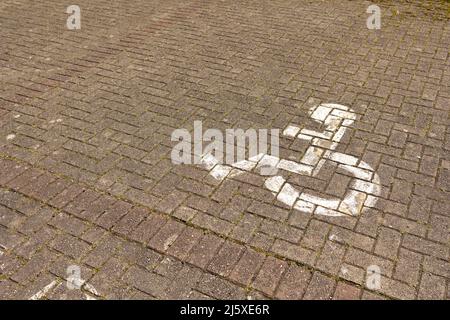 cartello di parcheggio per disabili bianco sulla strada di un parcheggio Foto Stock